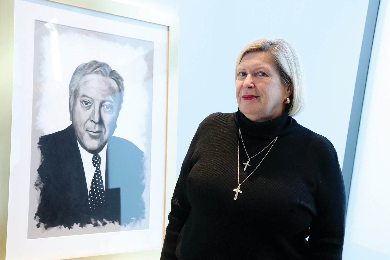 At the Papitto Opportunity Connection office in downtown Providence, Barbara Papitto smiles beside a portrait of her late husband Ralph Papitto.